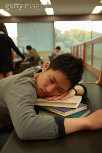 A boy is taking a nap in the library