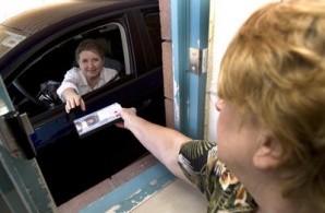 Volunteer Lauren Novoselac, right, hands a DVD to Mary Hall, Glendale, at the drive through window at the Foothills Library Branch in Glendale